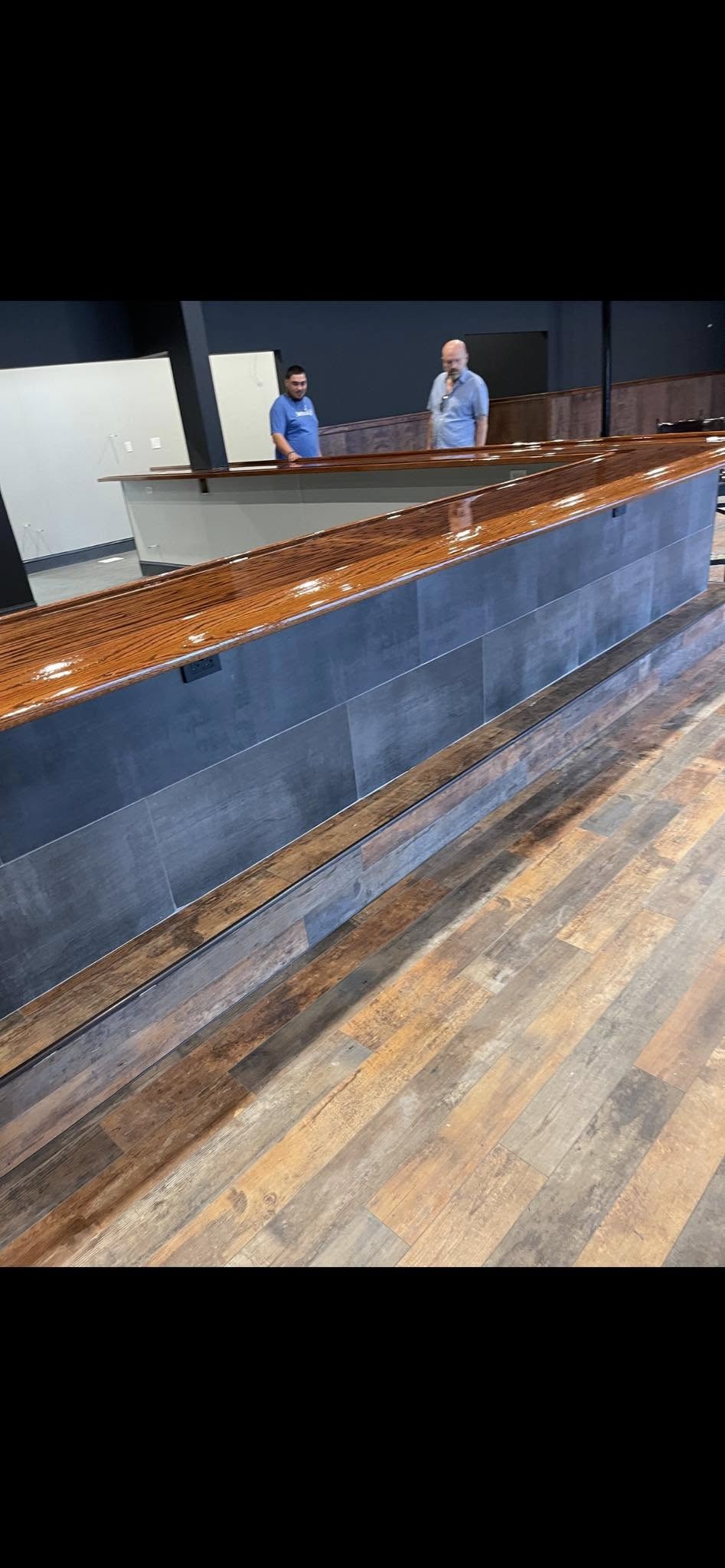 Actual JNL installation: wood-look plank flooring with a slate-toned tiled bar face